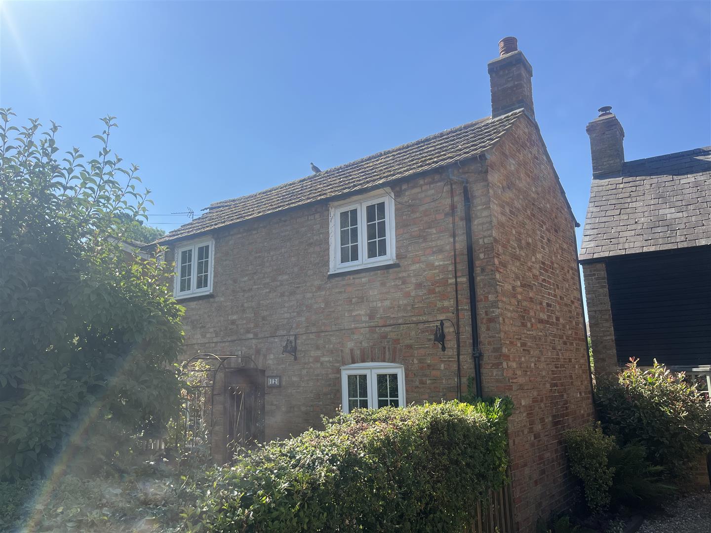 Charming brick cottage with tiled roof and hedge